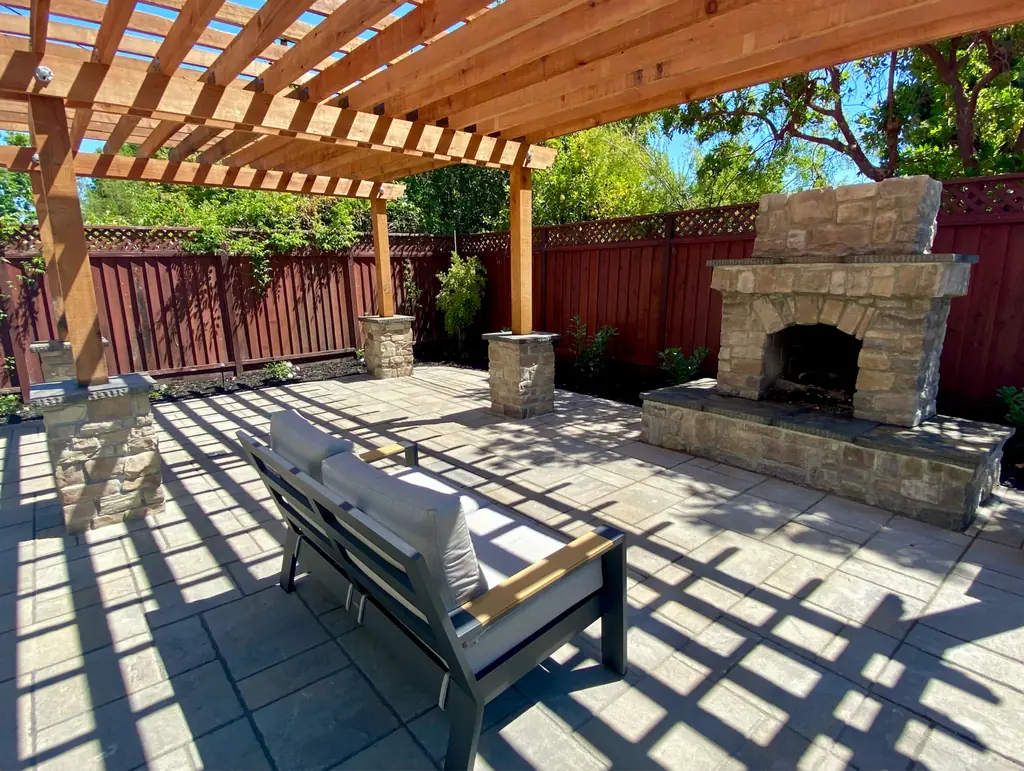 Pergola over a paver patio with an outdoor stone fireplace