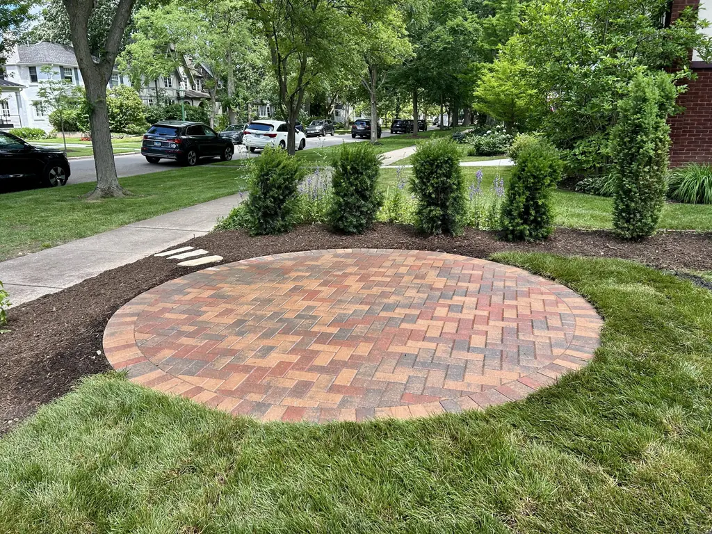 Round brick paver patio set into a lawn