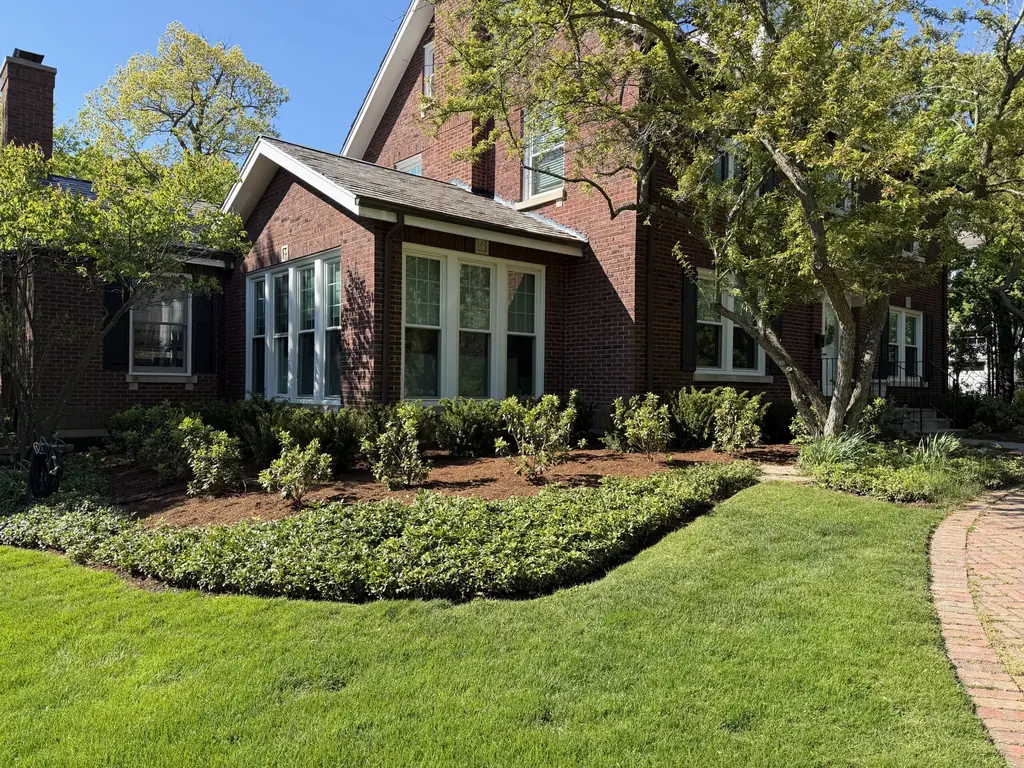 Healthy green lawn and planting beds in front of a brick home