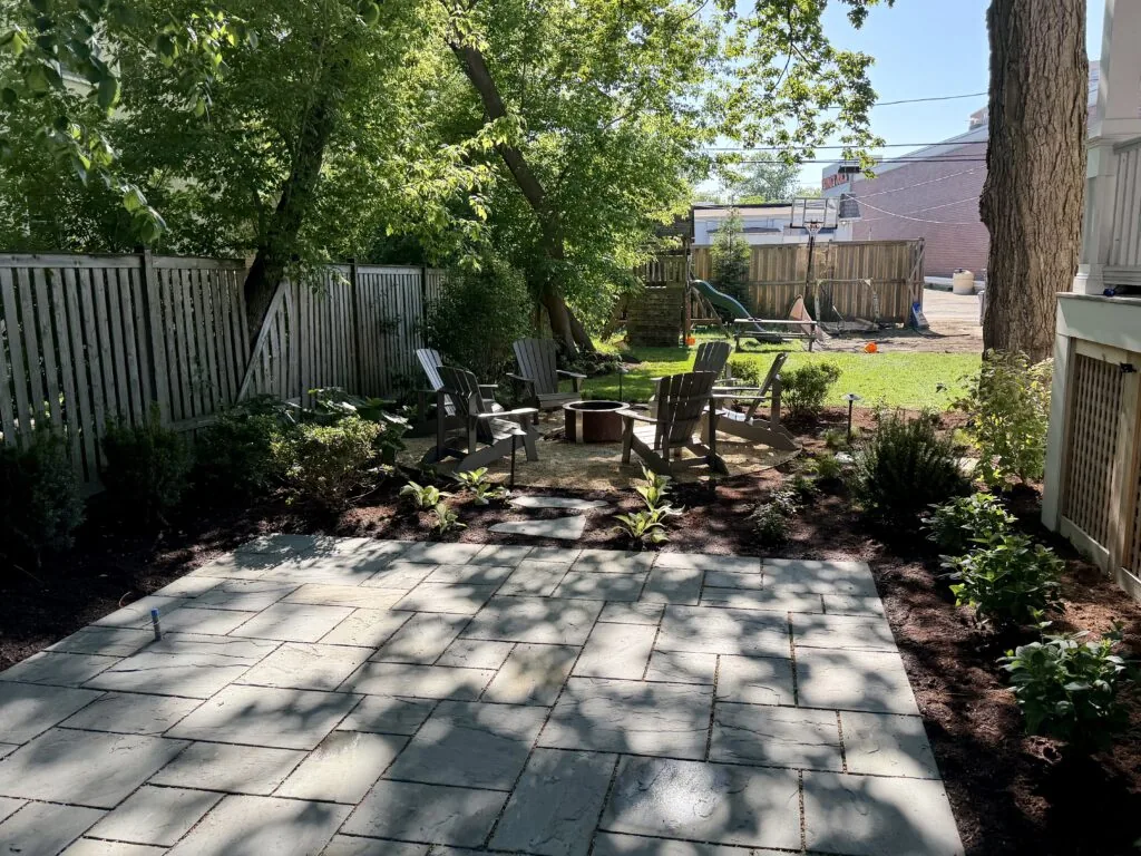Large natural stone paver patio in a shaded backyard