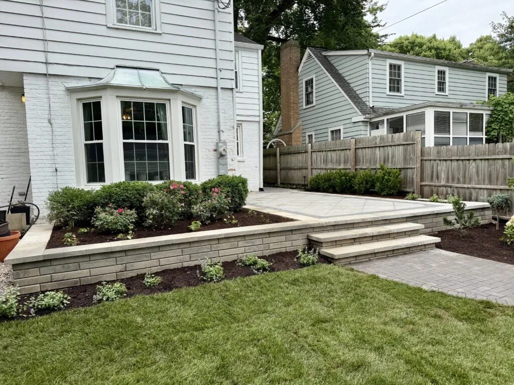 Lush lawn and planting beds around a raised paver patio