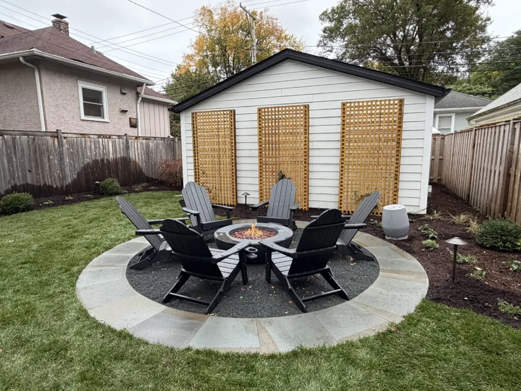 Backyard fire pit area with Adirondack chairs on a round patio