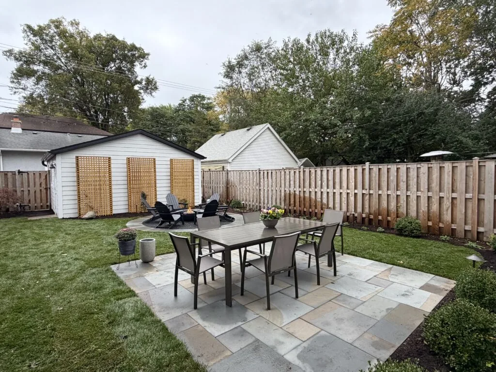 Natural stone patio with an outdoor dining set in a fenced backyard
