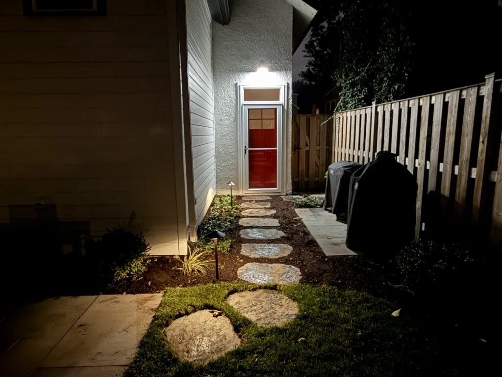 Lit stepping-stone path beside a home at night