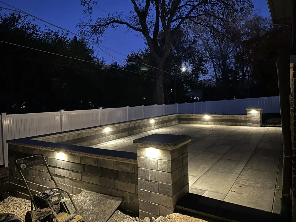 LED lighting built into a paver patio seat wall at night